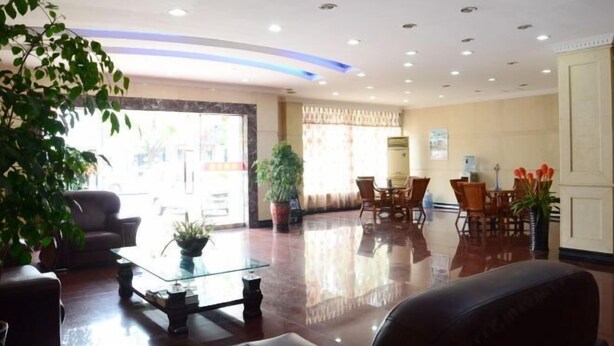 A hotel lobby with a glass coffee table, leather sofa, and a dining area with wooden chairs and a table. - Jinqiao Hotel (Anji)