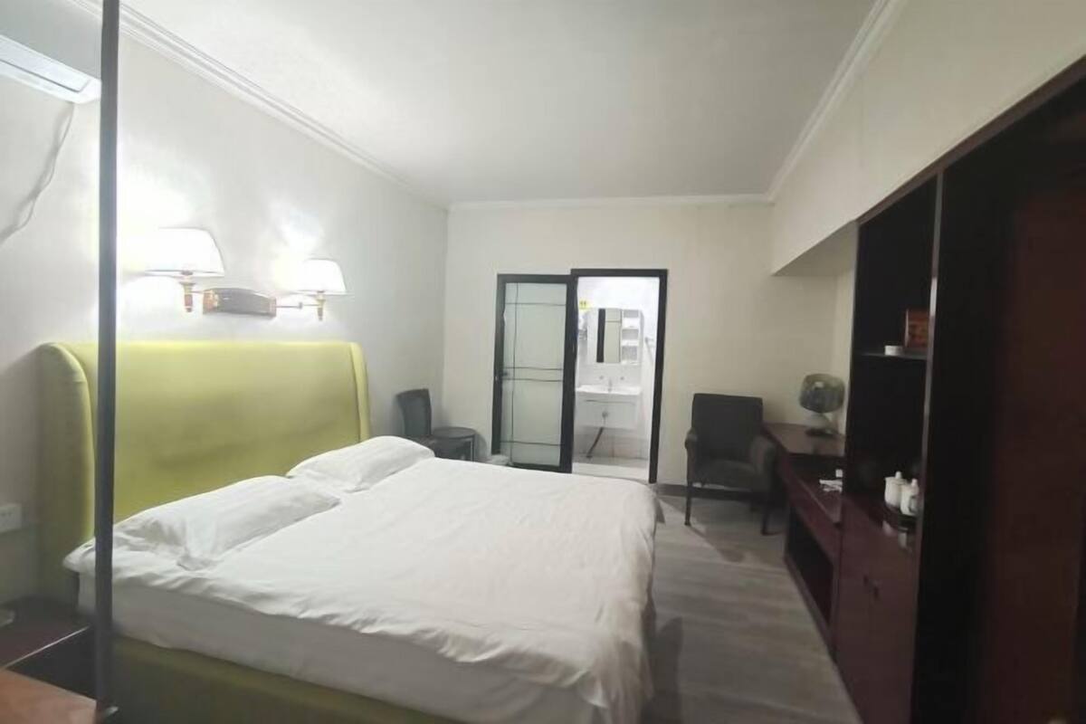 A hotel room with a bed, a desk, a chair, and a wardrobe.