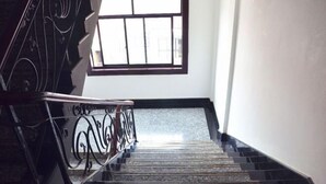 A staircase with a black railing and a window above. - Jinqiao Hotel (Anji)