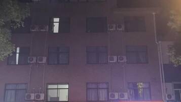 A building with multiple windows and a sign with red and white text.