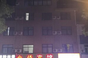 Un edificio con varias ventanas y un letrero con texto rojo y blanco.
