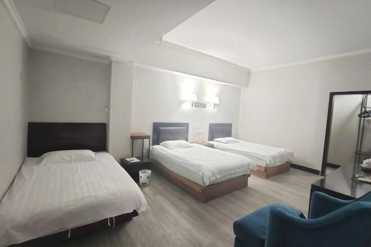 A hotel room with two beds, a desk, a chair, and a mirror.