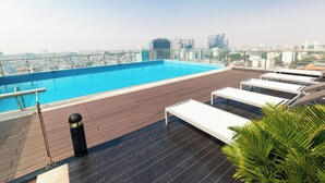 A rooftop pool with a city view, wooden deck, and lounge chairs.