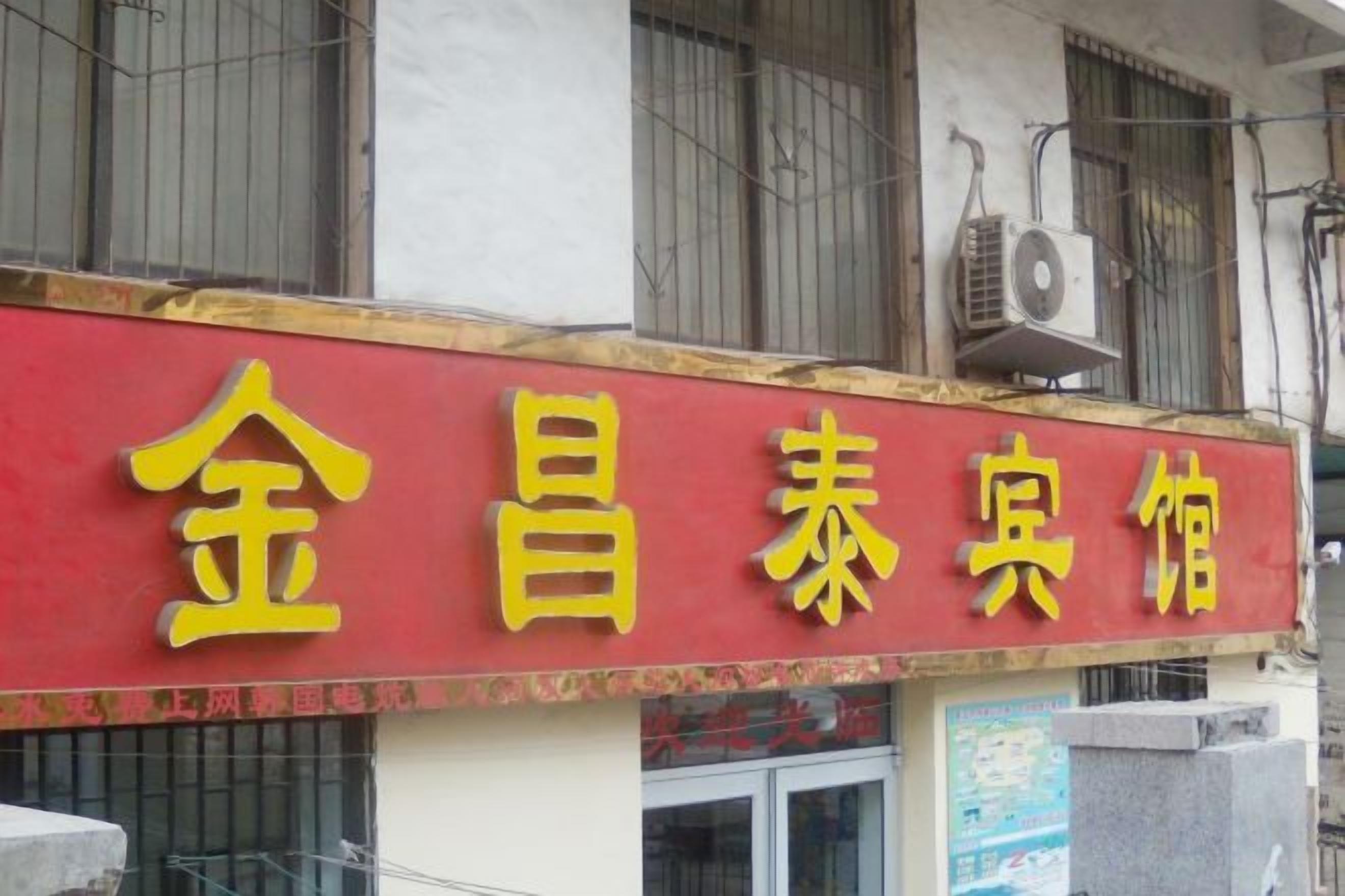 A building with a red and yellow sign that reads '金昌泰宾馆' (Jin Chang Tai Inn).