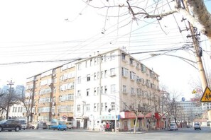Ein mehrstöckiges Gebäude mit einer flachen Fassade, mehreren Fenstern und einem sichtbaren Eingang.