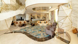 Een luxe lobby met marmeren vloer, een weelderige kroonluchter en een gebogen zithoek.