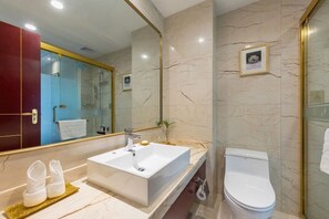 Ein modernes Badezimmer mit einem großen Spiegel, einem weißen Waschbecken und einer Toilette.