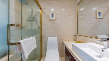 A bathroom with a glass-enclosed shower, a white toilet, and a large sink with a mirror.