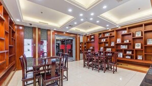 A hotel lobby with a central dining area, wooden bookshelves, and a tiled floor. - Yilong Hotel (Jingdezhen)