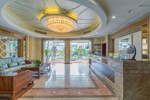 Un hall d’hôtel avec un magnifique lustre, un comptoir d’accueil et une vue sur l’extérieur.
