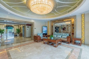 A spacious lobby with a chandelier, sofas, and a television. - Yilong Hotel (Jingdezhen)