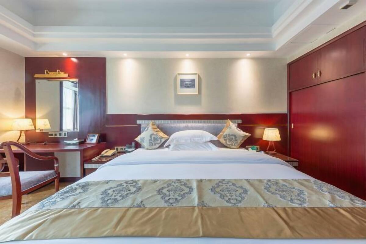 Una habitación de hotel con una cama grande, mesitas de noche, un escritorio, una silla y un armario.