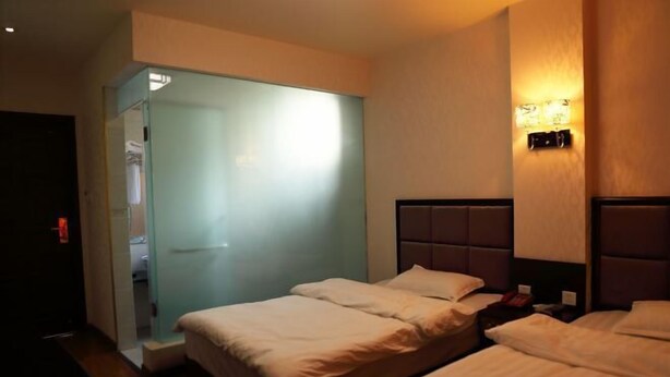 A hotel room with two beds, a walk-in closet, and a wall-mounted light fixture. - Kangding Dongsheng Business Hotel (Kangding)