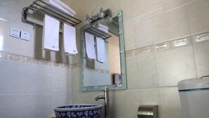 A bathroom with a blue floral bowl sink, a mirror with a towel rack above it, and a towel dispenser. - Kangding Dongsheng Business Hotel (Kangding)