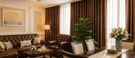 A luxurious living room with a brown leather sofa, a dining table, and a chandelier.