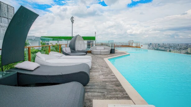 A rooftop infinity pool with lounge chairs and a city view. - Salute de Léman - Luxury Apartment District 3 (Ho Chi Minh City)