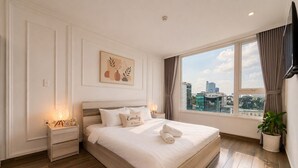 A modern bedroom with a large bed, bedside tables, a city view, and a framed artwork on the wall. - Salute de Léman - Luxury Apartment District 3 (Ho Chi Minh City)