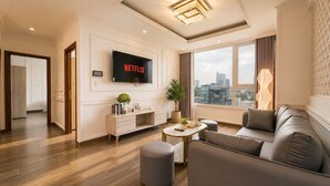 A modern living room with a flat-screen TV, a sofa, a coffee table, and a view of the city. - Salute de Léman - Luxury Apartment District 3 (Ho Chi Minh City)