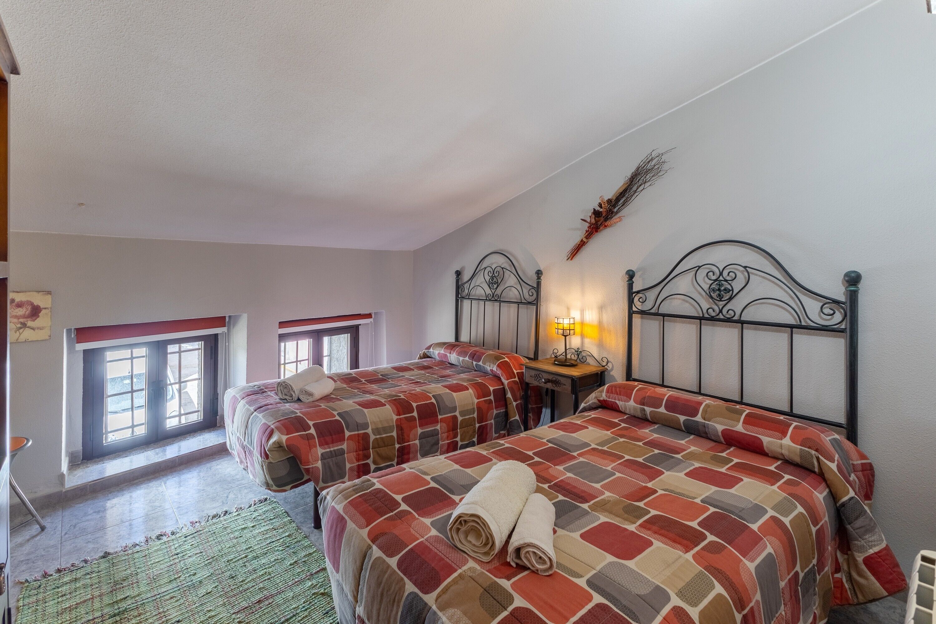 Un dormitorio con dos camas, una ventana, una mesita de noche con lámpara y un adorno en la pared.