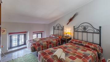Un dormitorio con dos camas, una ventana, una mesita de noche con lámpara y un adorno en la pared.