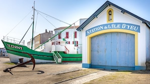 A building labeled 'STATION de L'ILE D'YEU' with a green and white boat docked outside.