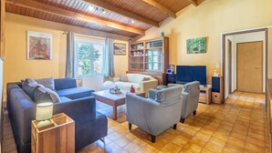 A living room with a sofa, armchairs, a coffee table, a bookshelf, and a television.