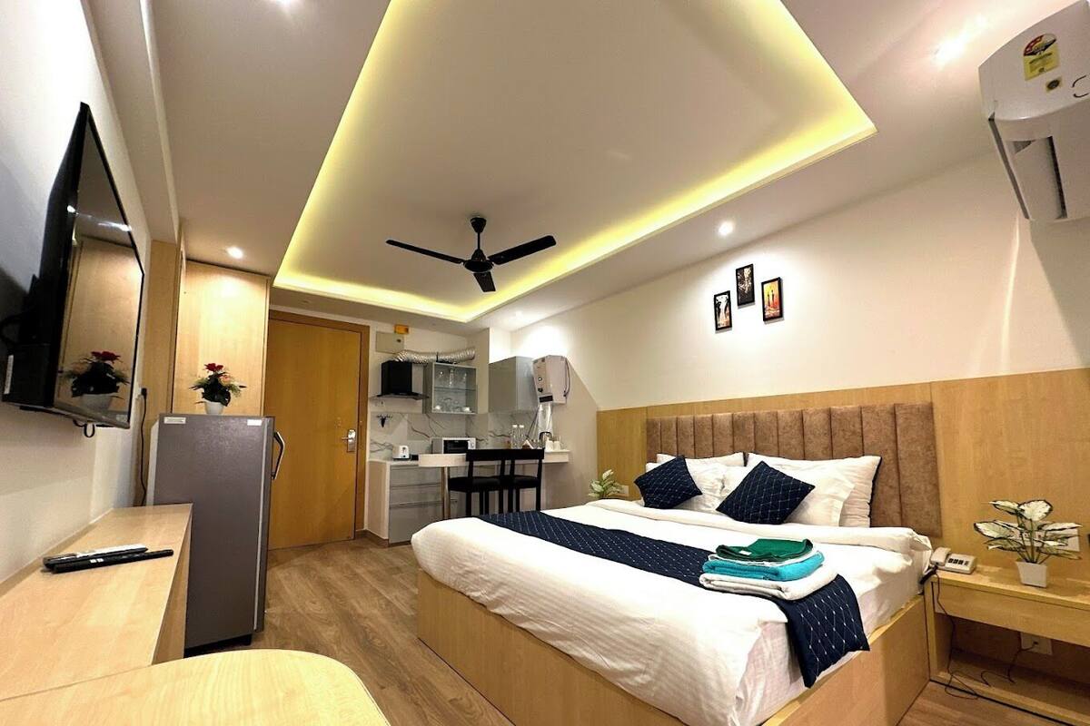 Une chambre d’hôtel moderne équipée d’un lit, d’une table de chevet, d’un bureau et d’un coin cuisine.