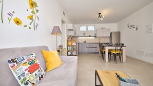 A modern living room with a sofa, a coffee table, and a dining area with chairs and a table. - Apartment 'New Casa Tiberio' with Shared Pool, Wi-Fi and Air Conditioning (Lazise)