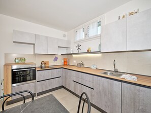 Una cucina moderna con forno integrato, macchina da caffè e lavandino.