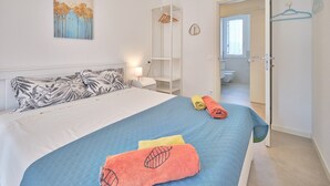 A bedroom with a bed, a painting, a wardrobe, a bathroom visible through an open door, and a coat hanger. - Apartment 'New Casa Tiberio' with Shared Pool, Wi-Fi and Air Conditioning (Lazise)