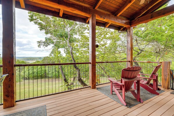 A wooden deck with a view of a forest and a distant landscape. - Lake Travis Views! Hollows Cabin, Pools, Sleeps 10 (Jonestown)