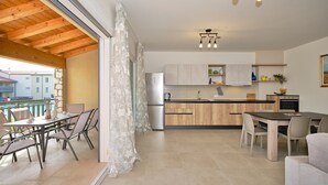 A modern kitchen with wooden cabinets, a refrigerator, and a dining area with a table and chairs.