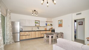 A modern kitchen with wooden cabinets, a stainless steel refrigerator, and a dining area with a table and chairs.