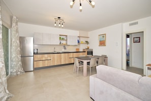 A modern kitchen with wooden cabinets, a stainless steel refrigerator, and a dining area with a table and chairs. - Apartment 'New Casa Augusto' with Shared Pool, Wi-Fi and Air Conditioning (Lazise)
