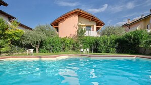 A swimming pool with a house in the background. - Apartment 'Madonnina  In Lazise' with Shared Pool, Wi-Fi and Air Conditioning (Lazise)