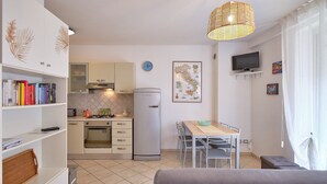 A compact kitchen with a gas stove, a refrigerator, and a dining area with a table and chairs. - Apartment 'Madonnina  In Lazise' with Shared Pool, Wi-Fi and Air Conditioning (Lazise)