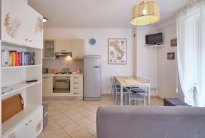 Cocina compacta con estufa a gas, refrigerador y comedor con mesa y sillas.