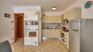 A compact kitchen with a refrigerator, stove, and a small dining area. - Apartment 'Madonnina  In Lazise' with Shared Pool, Wi-Fi and Air Conditioning (Lazise)