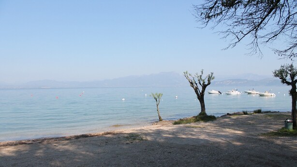 A beach with boats, trees, and a clear sky. - Apartment 'Madonnina  In Lazise' with Shared Pool, Wi-Fi and Air Conditioning (Lazise)