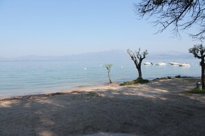 A beach with boats, trees, and a clear sky. - Apartment 'Madonnina  In Lazise' with Shared Pool, Wi-Fi and Air Conditioning (Lazise)