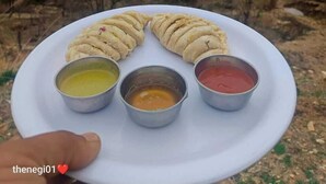 Ein Teller mit Fladenbrot und vier verschiedenen Dips, vor einer Bergkulisse.