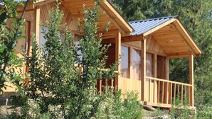 Eine Holzhütte mit Veranda, umgeben von viel Grün.
