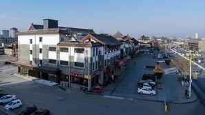 A street view of a traditional building with multiple floors, a mix of commercial and residential spaces, and a parking area.
