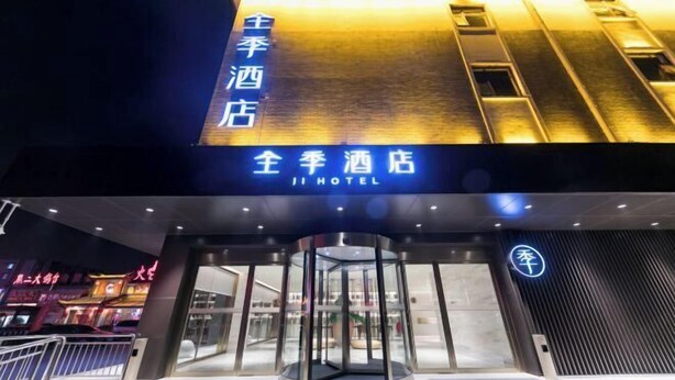 The exterior of Ji Hotel with a revolving door entrance and illuminated signage.