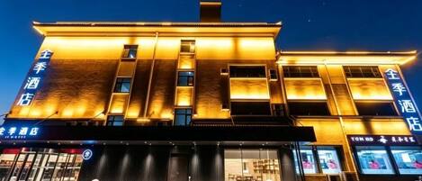A hotel with a modern facade, illuminated signage, and a prominent entrance.