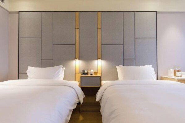 Una habitación de hotel con dos camas, una mesita de noche con lámpara y un diseño de panel en la pared.