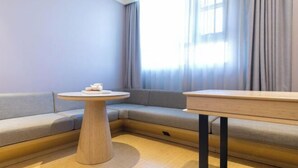 A modern room with a sofa, a round wooden table, and a small wooden cabinet.