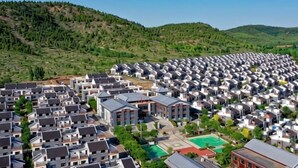 A residential area with modern houses, a central building, and a green space with a basketball court.