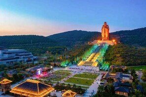 A large statue on a hill with a descending staircase, surrounded by a park and residential buildings. - JI Hotel (Qufu Tourist Center) (Qufu)