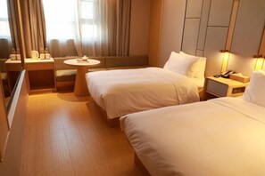 Habitación de hotel con dos camas, una mesita redonda pequeña, un sofá y un escritorio con lámpara.